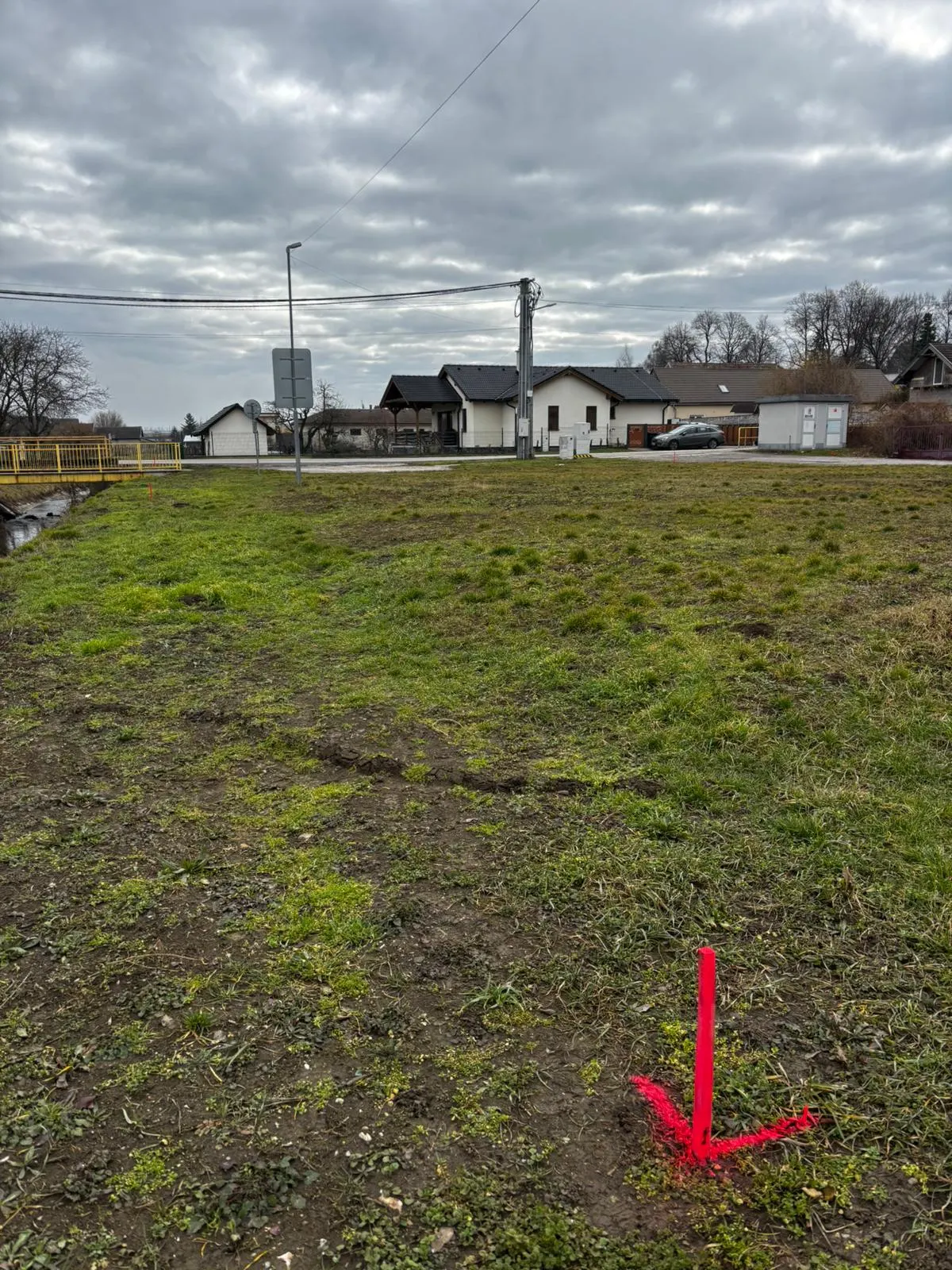 BEFORE — view across the plot towards the neighbouring family housing and village infrastructure.