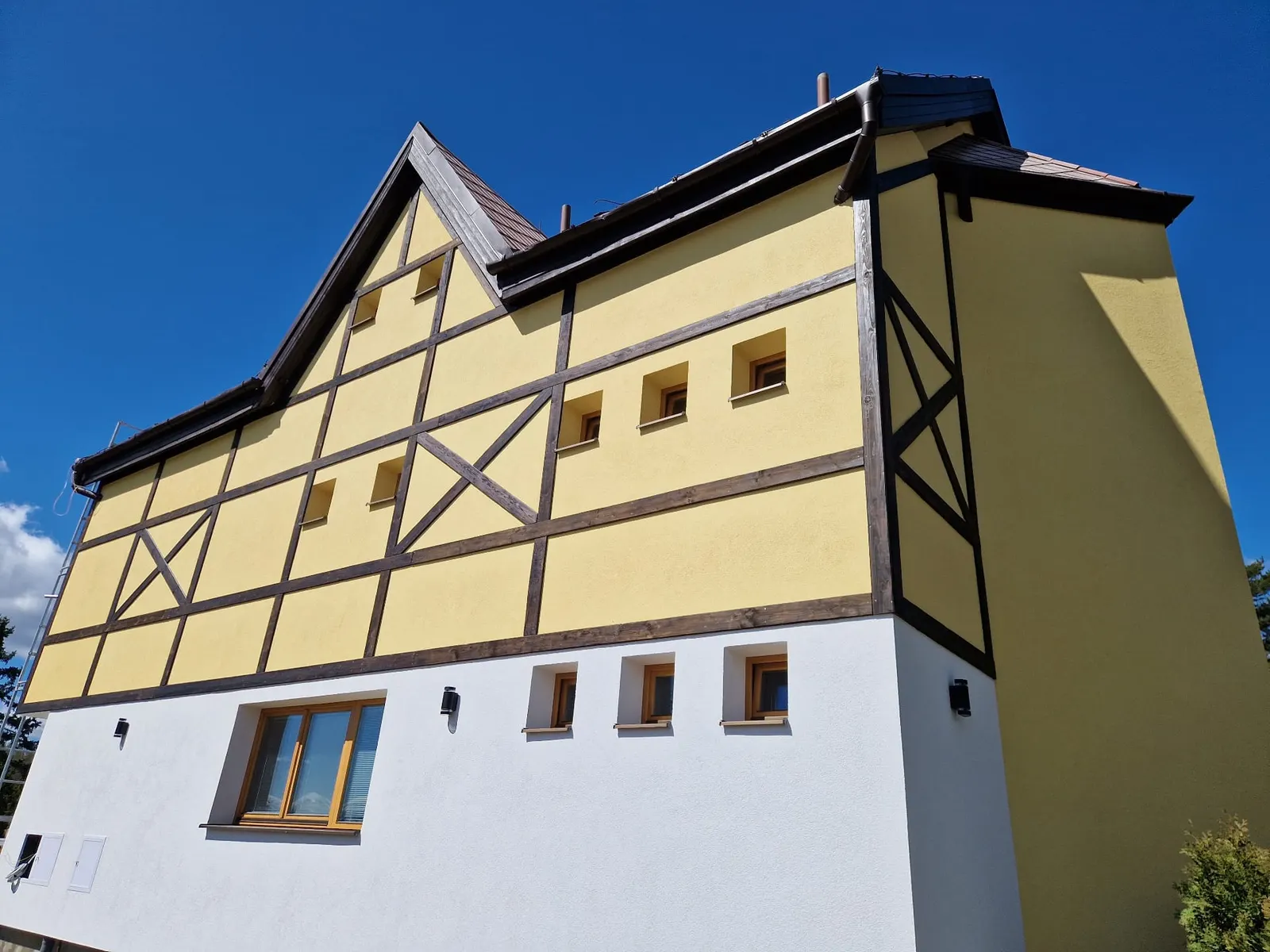 Hikers Paradise — side façade after the renovation (2025) with visible timber framing, new render and a white plinth.
