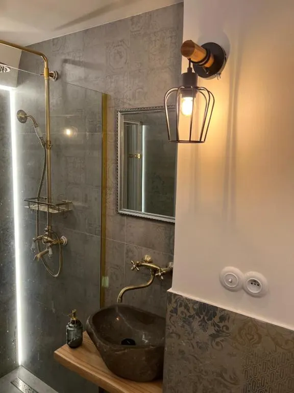 Bathroom — natural stone, brass fixtures, ornamental grey tiles — craft execution.