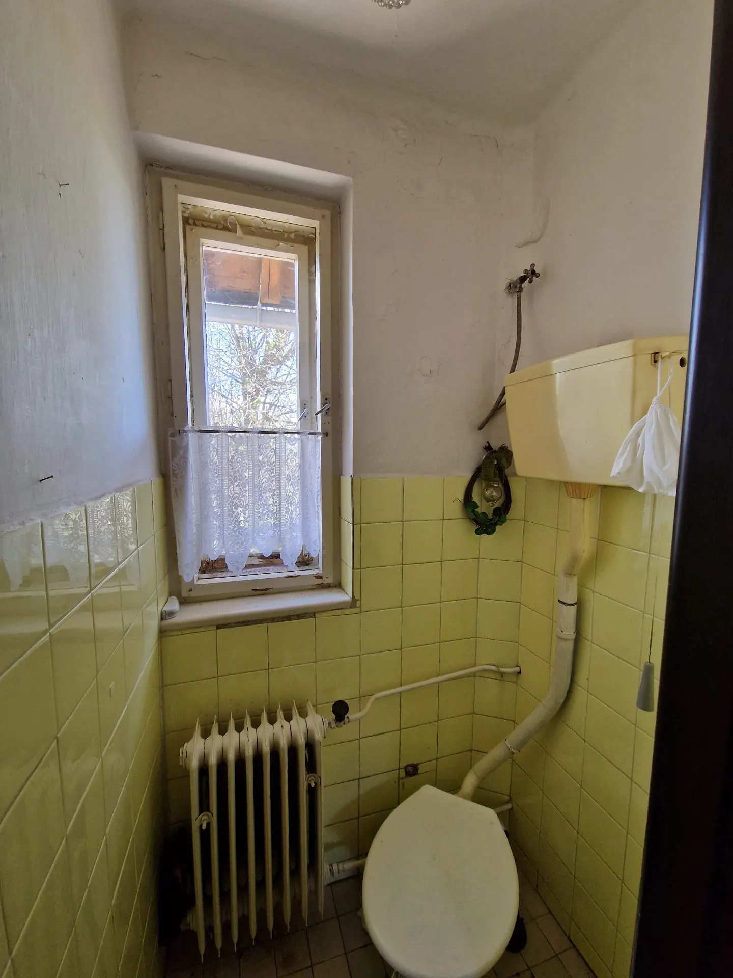 BEFORE renovation (05/2025) — original toilet with yellow tiles, a cast-iron radiator and old-style cistern. The space will be completely demolished and replaced with a new layout.