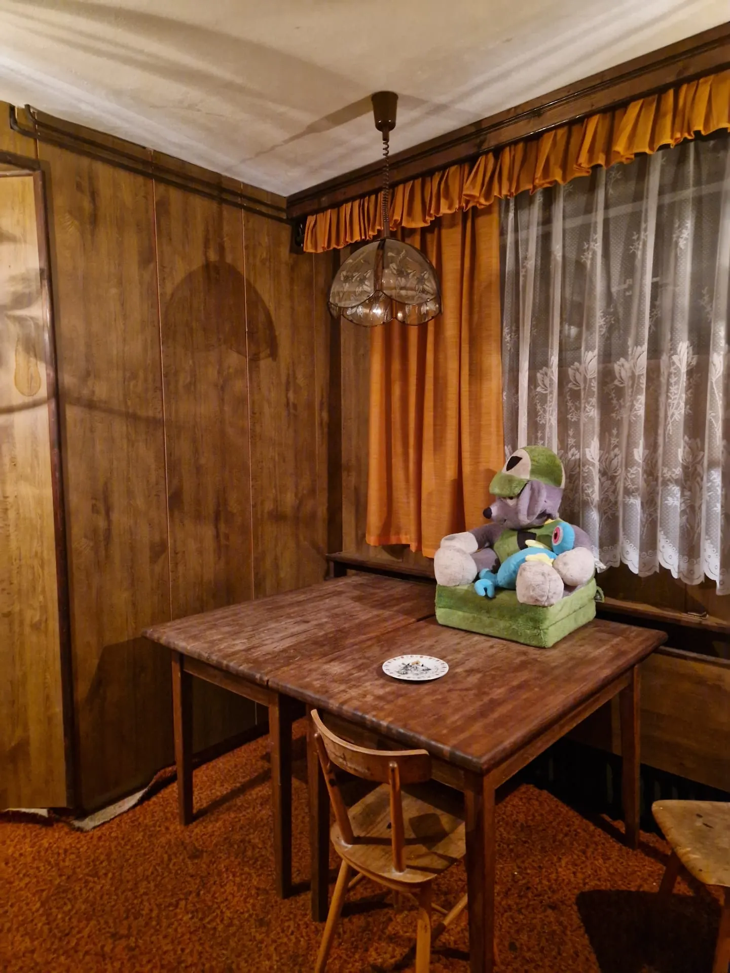 BEFORE renovation (08/2024) — original dining room with wood-panelled walls, a period table and orange curtains.